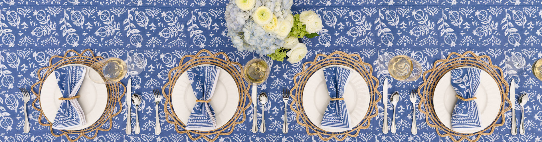 pomegranate blue napkins on white plate with wicker chargers and bamboo napkin rings