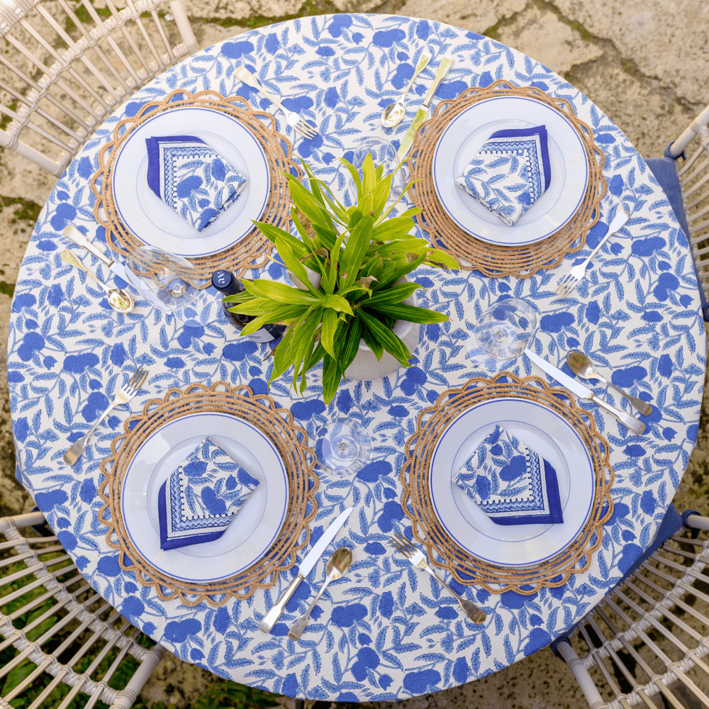 Table setting with plates, napkins, and cutlery on a floral tablecloth.