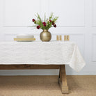 An ivory tablecloth with an embroidered diamond pattern on a white background