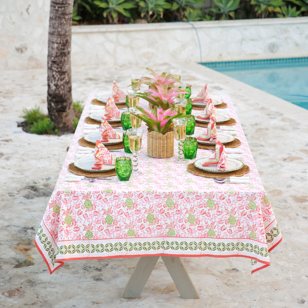 Dining table set for a meal outdoors with a pool in the background.