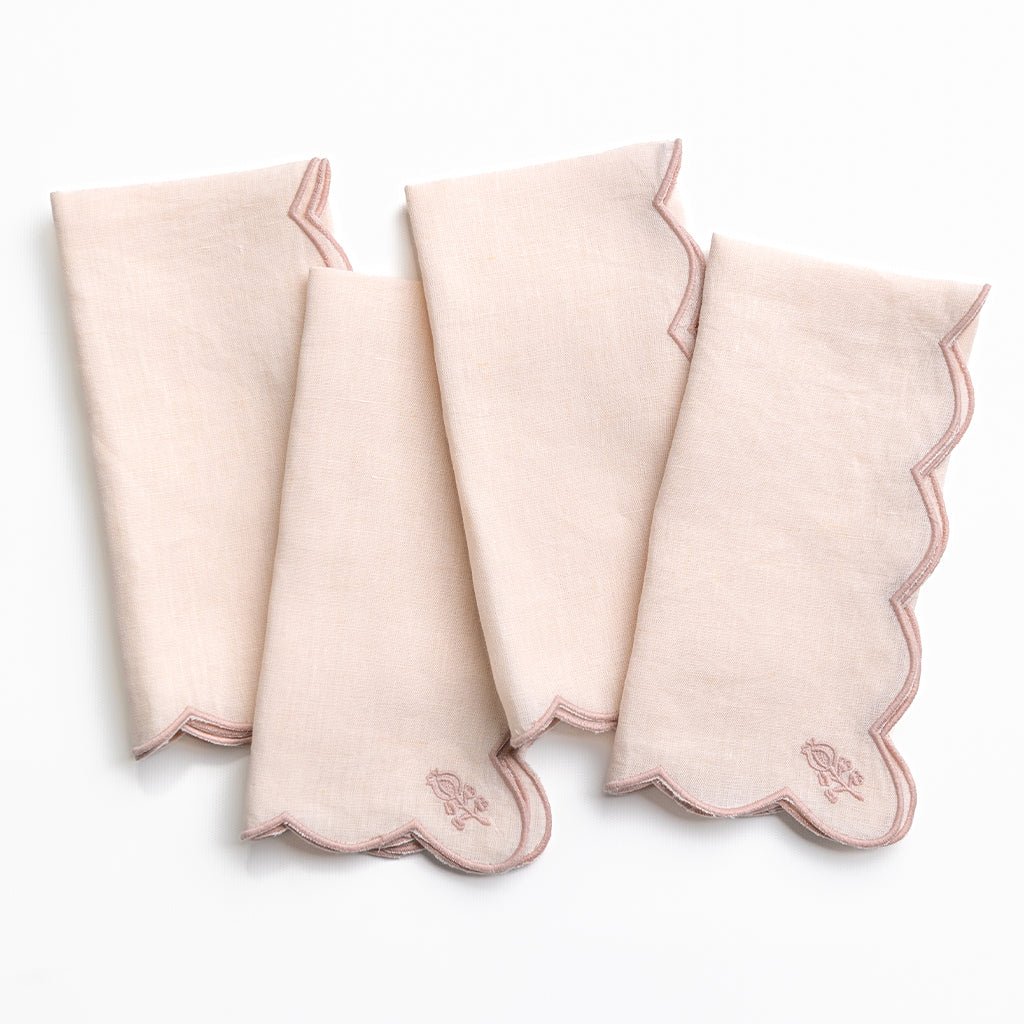 Set of four pink napkins with scalloped edges on a white background
