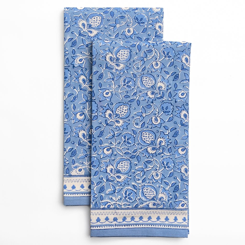 Two blue patterned towels with white floral designs on a white background