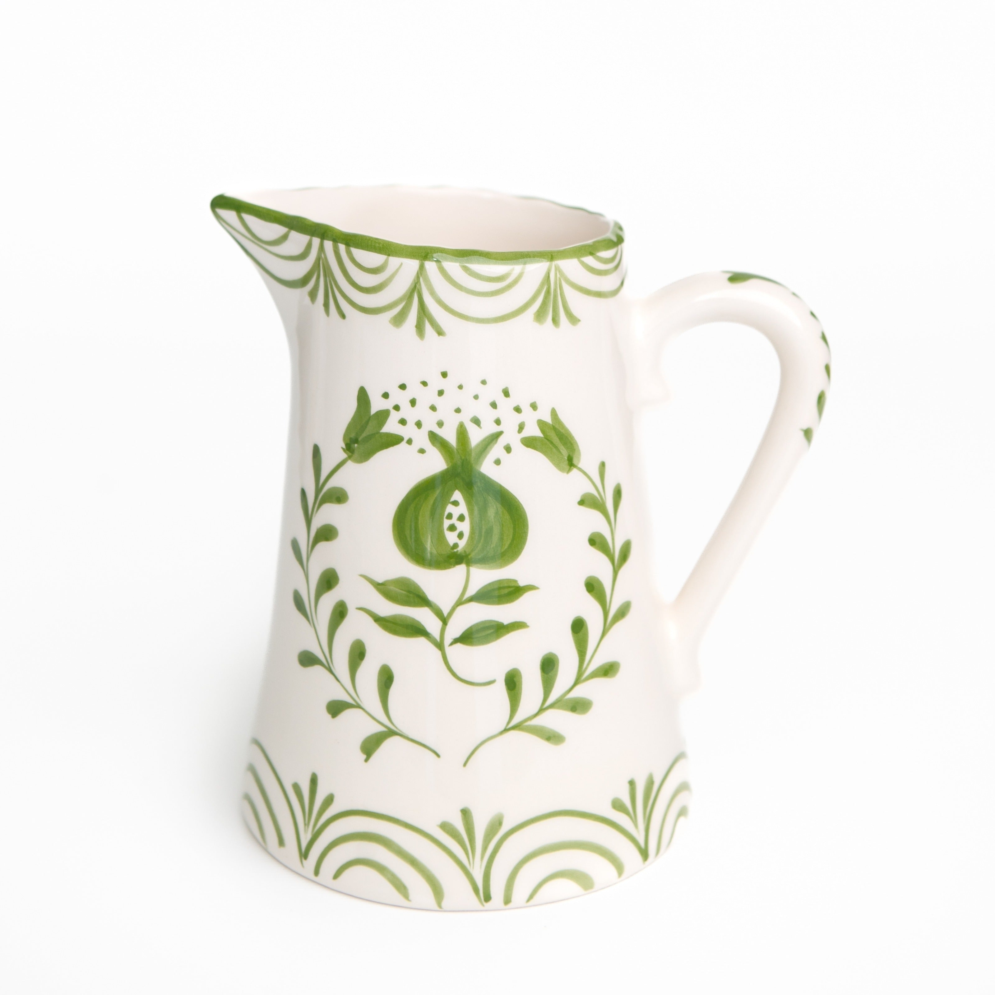 White ceramic pitcher with green floral patterns on a white background