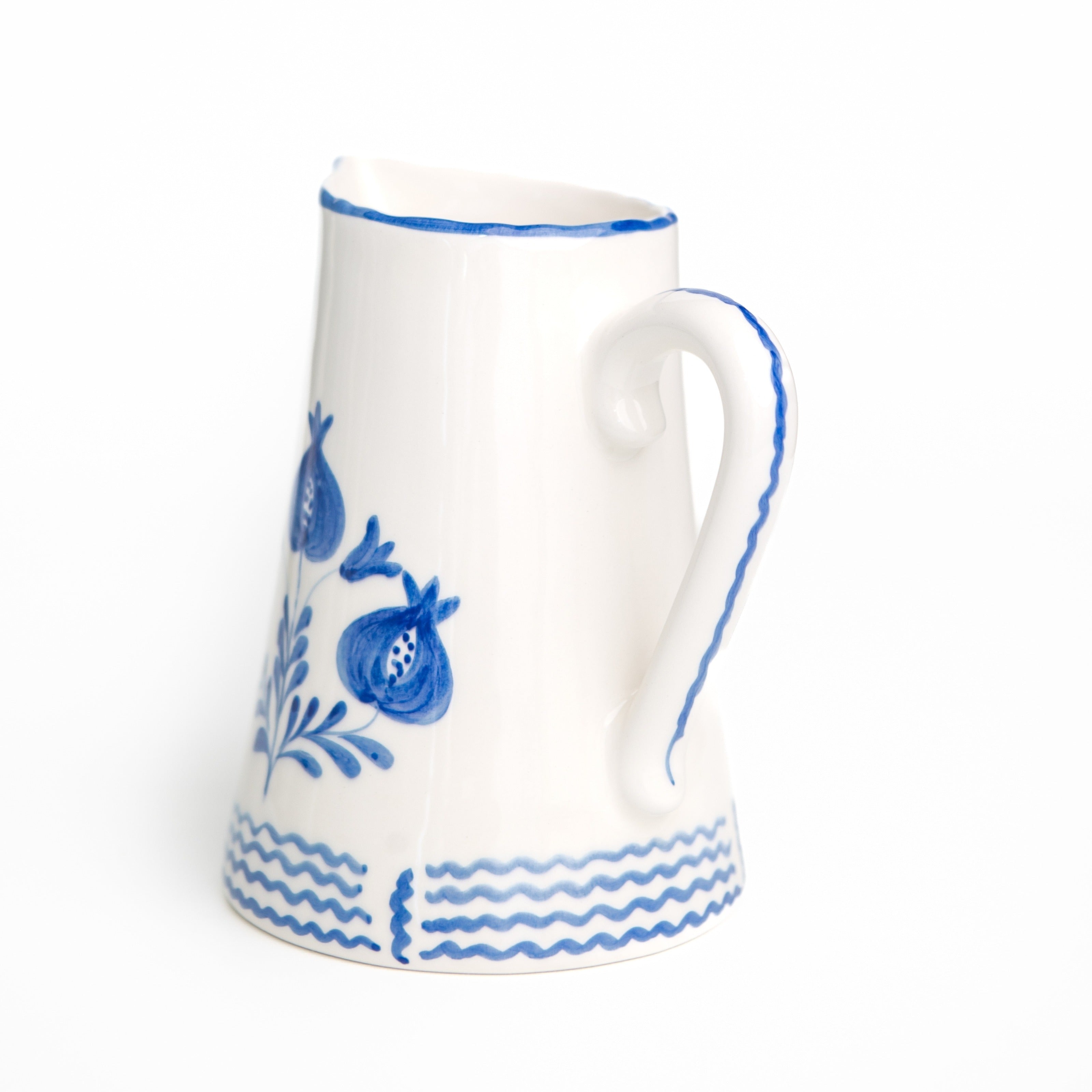 White ceramic pitcher with cobalt blue floral and wave patterns on a white background