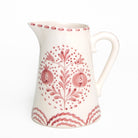 White ceramic pitcher with rose floral patterns on a white background