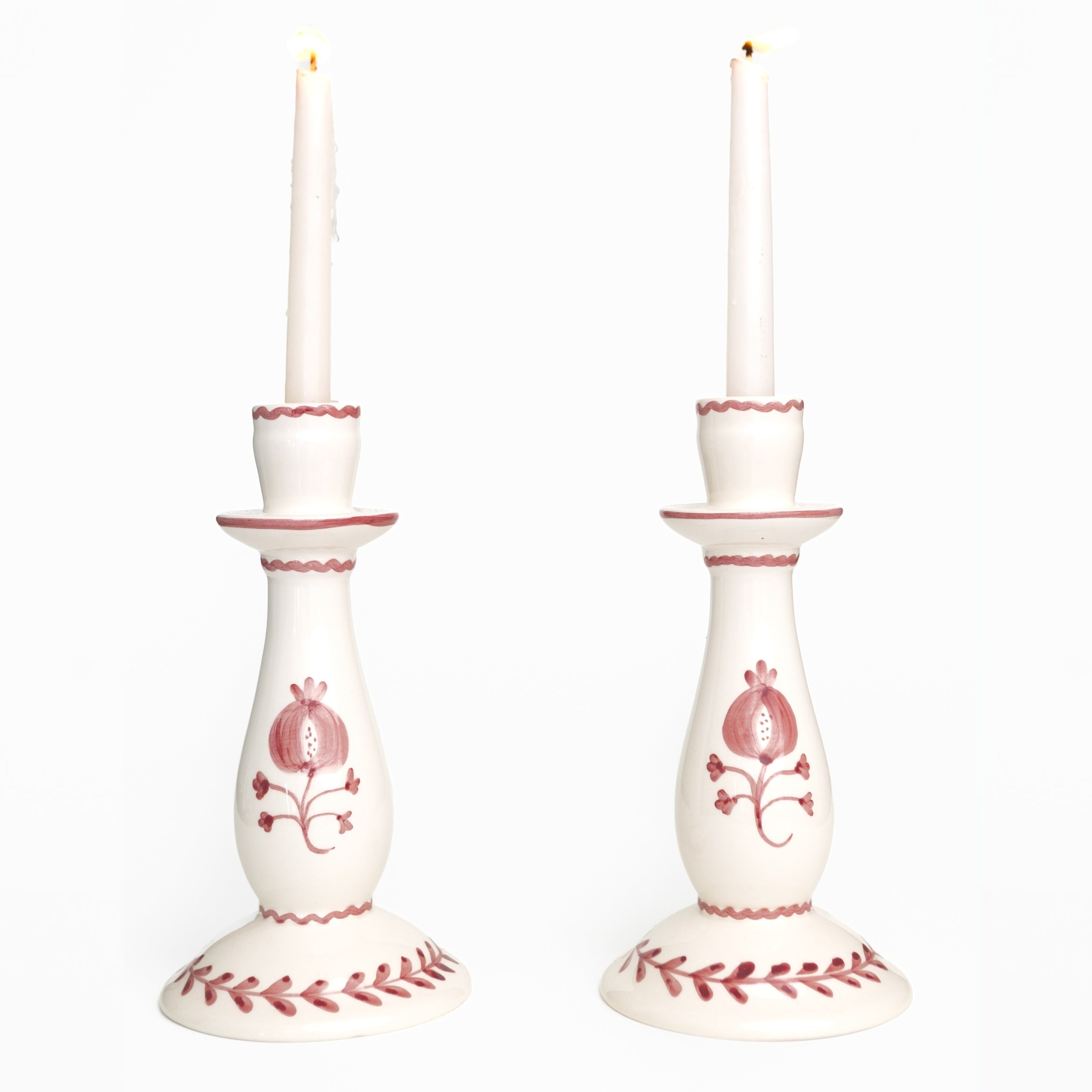 Pair of white candlesticks with red floral patterns on a white background