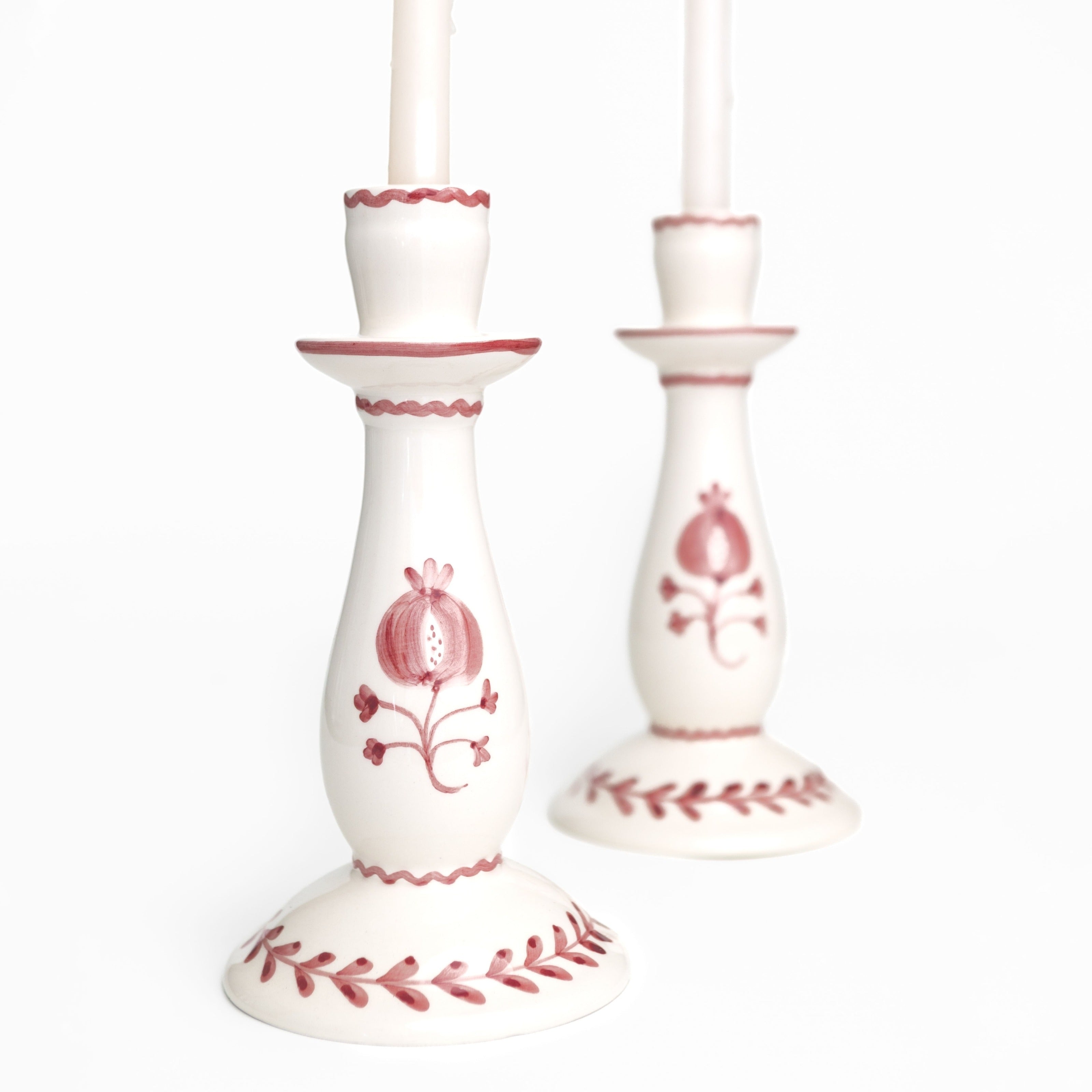White candle sticks with red floral designs on a white background