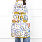 Woman wearing a blue floral apron with a belt on a white background
