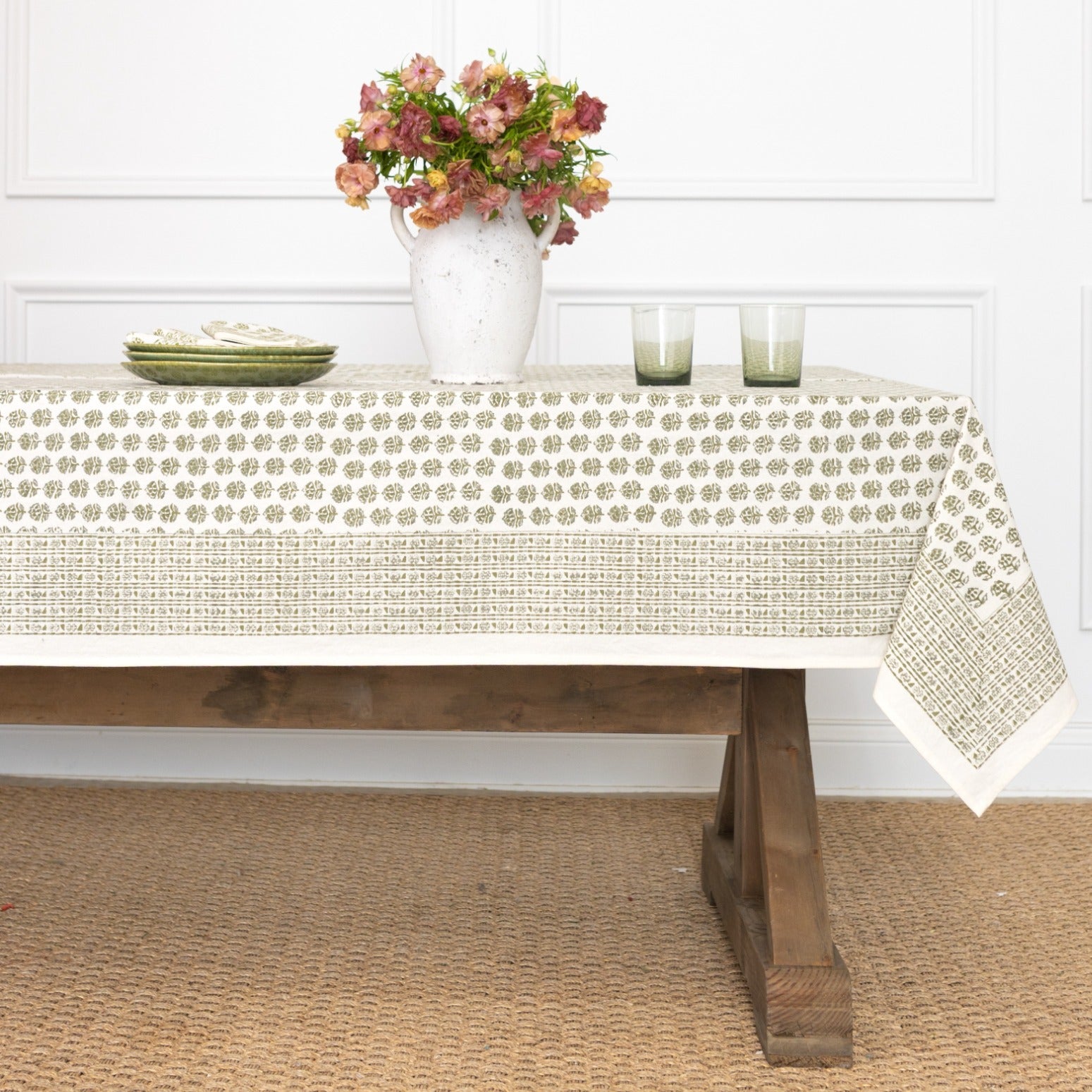 Table with a floral arrangement, candles, and a patterned tablecloth.