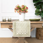 Wooden table with a floral arrangement, candles, and a patterned table runner.