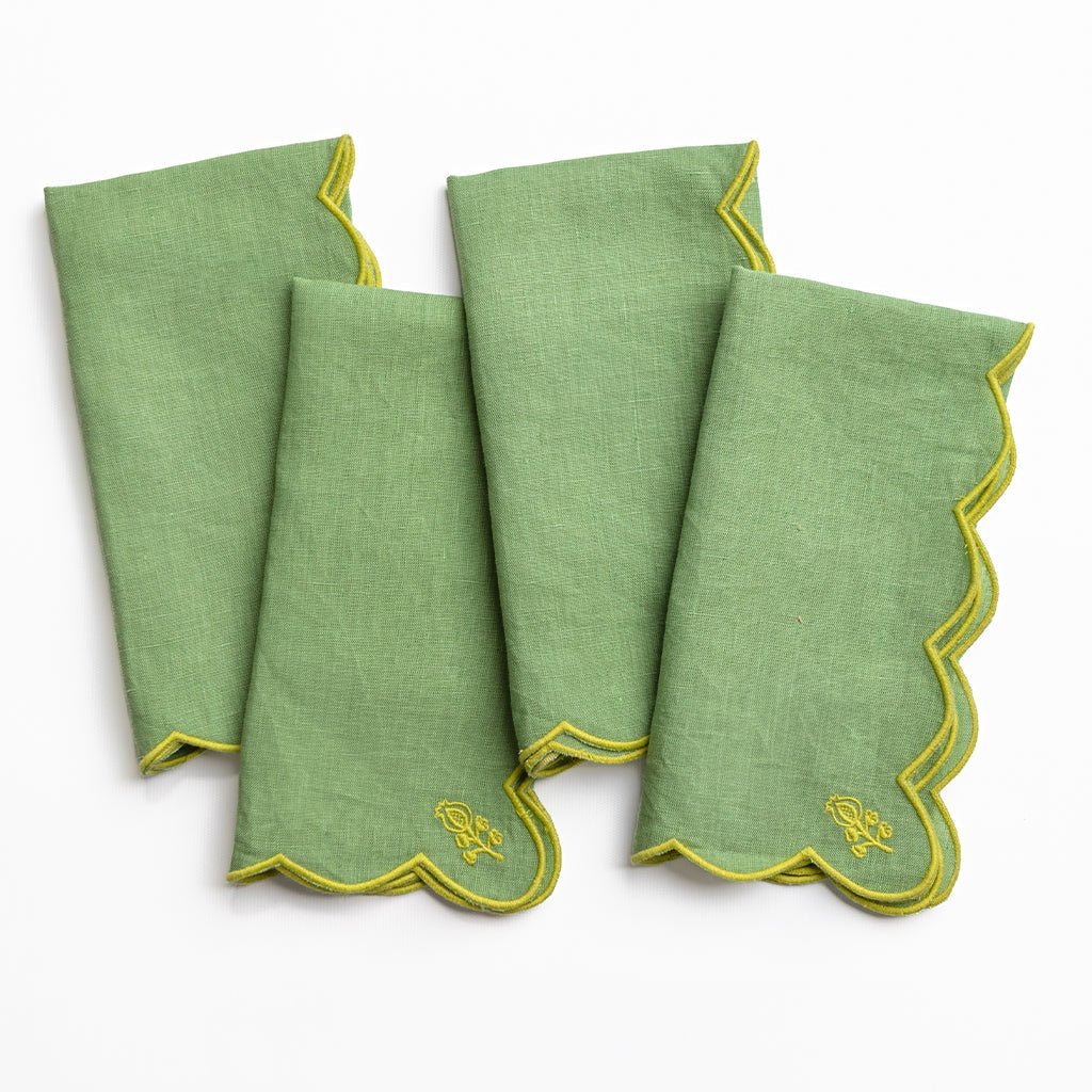 Set of four green napkins with yellow trim on a white background