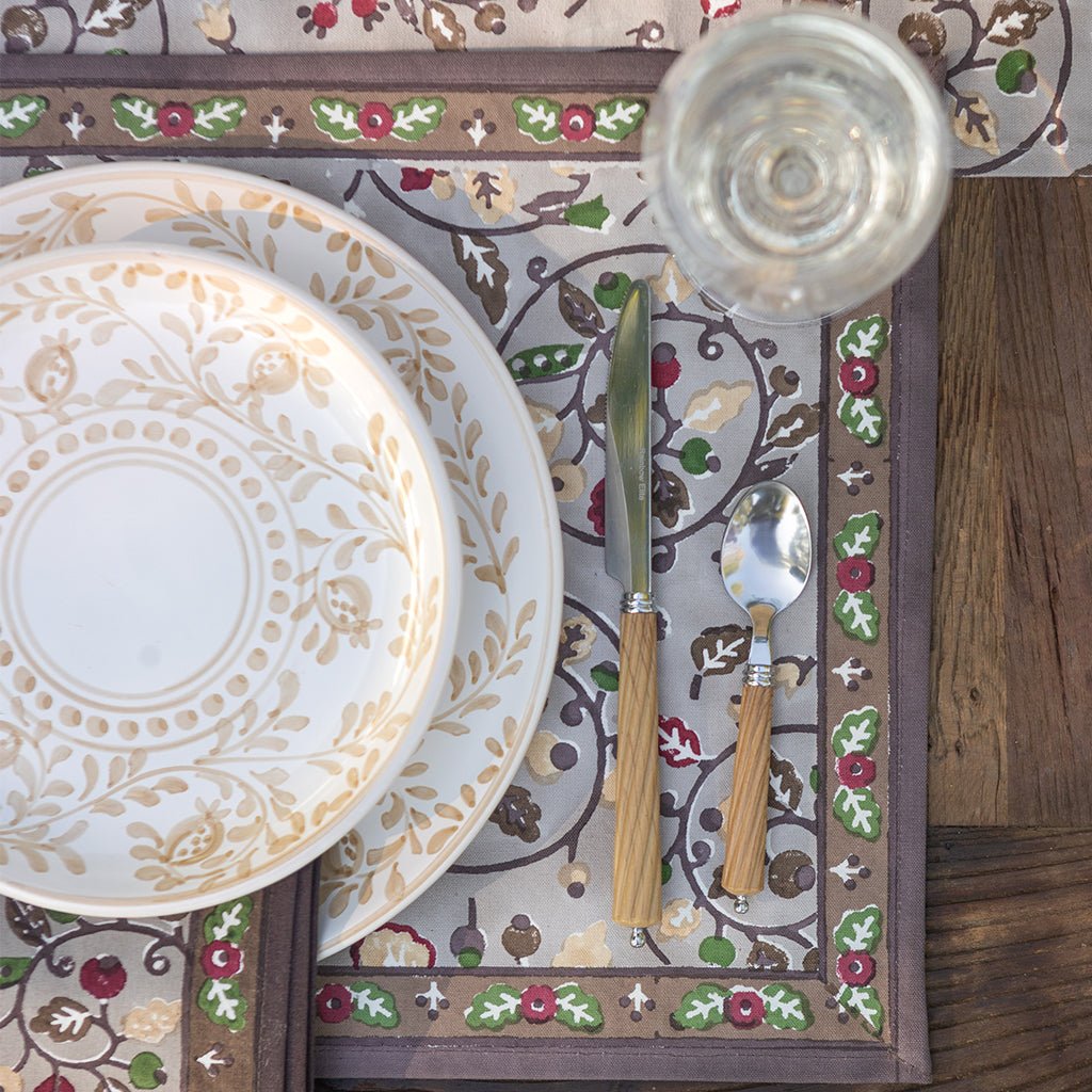 Decorative table setting with floral plates, cutlery, and a patterned placemat.