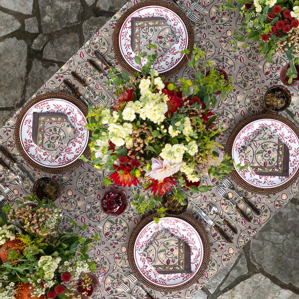 Decorative table setting with patterned plates, flowers, and cutlery on a textured surface.