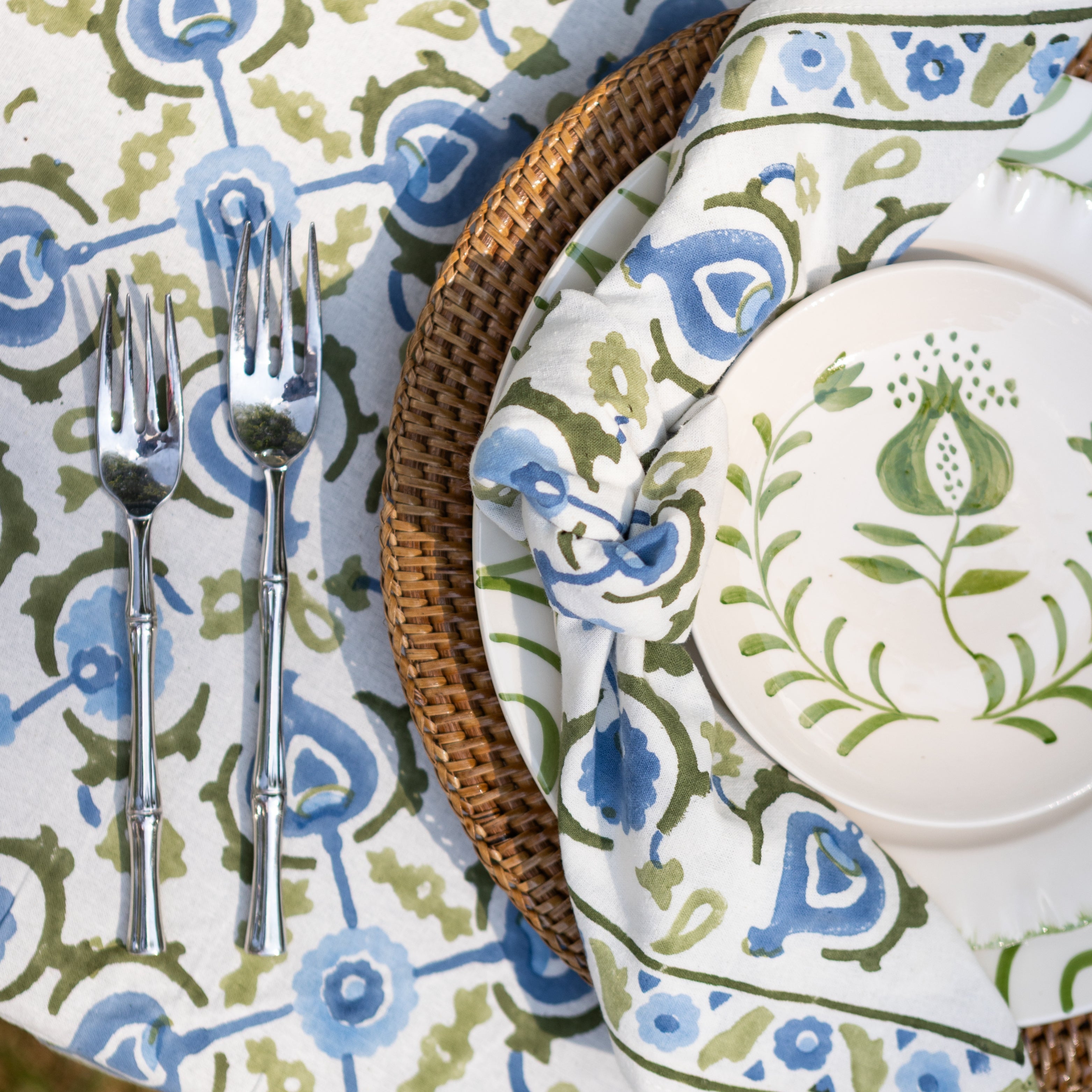Dining table setting with patterned tablecloth, plate, and cutlery.