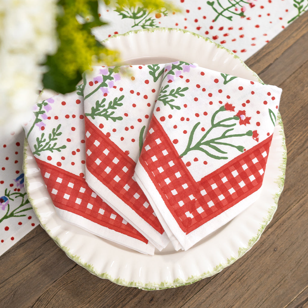 Set of red and white patterned napkins on a paper plate with a wooden surface background.