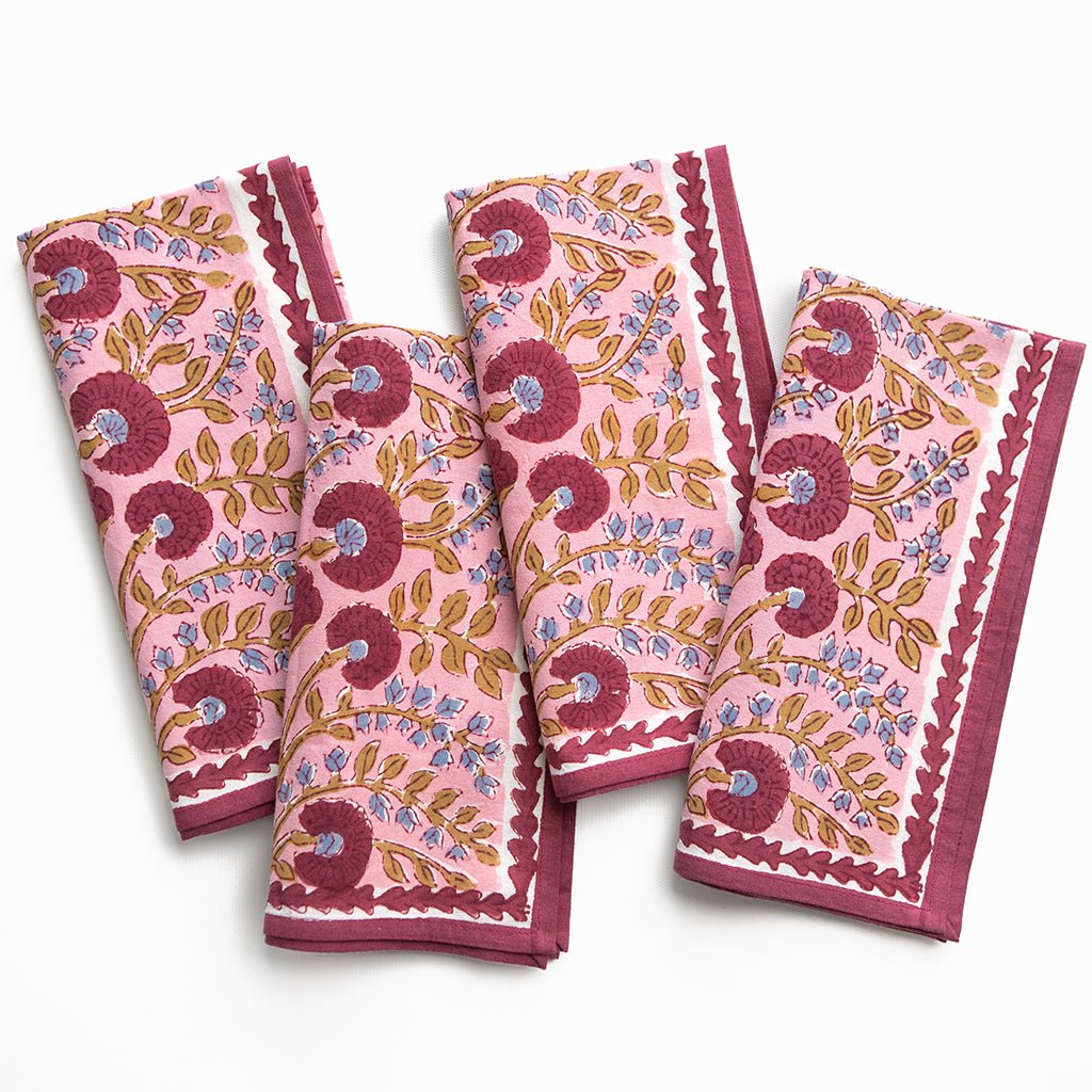 Set of four pink floral patterned napkins on a white background