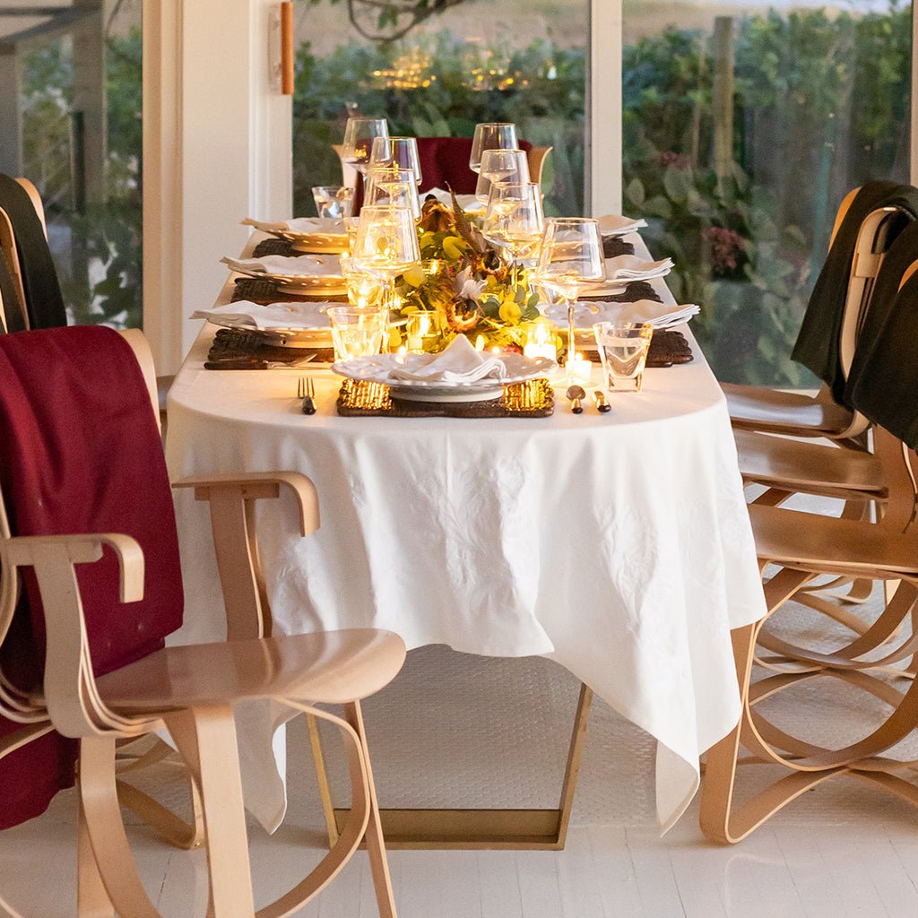Dining table set with plates, glasses, and a centerpiece in a bright room.