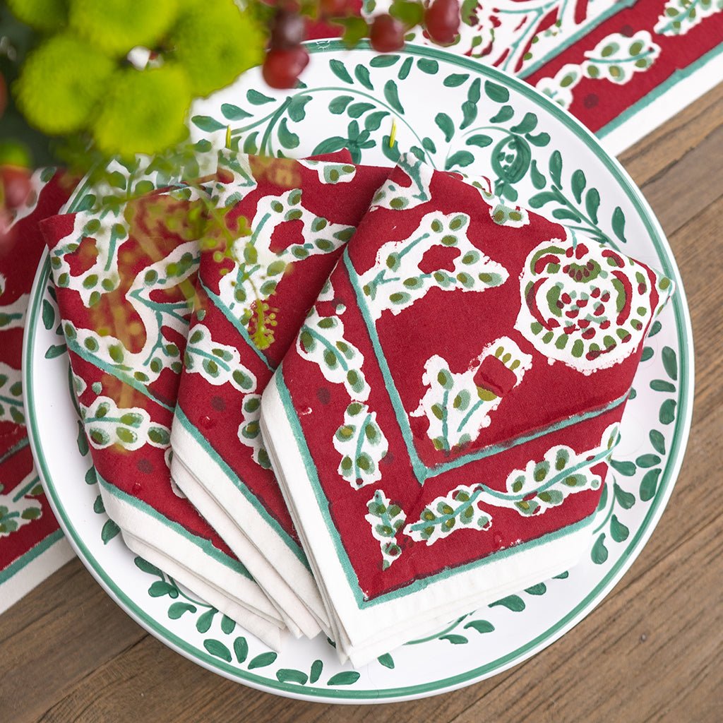 Red and green patterned napkins on a white plate with green trim.