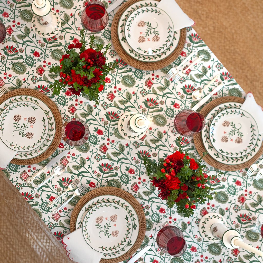 Decorative table setting with floral tablecloth, plates, and red glassware.