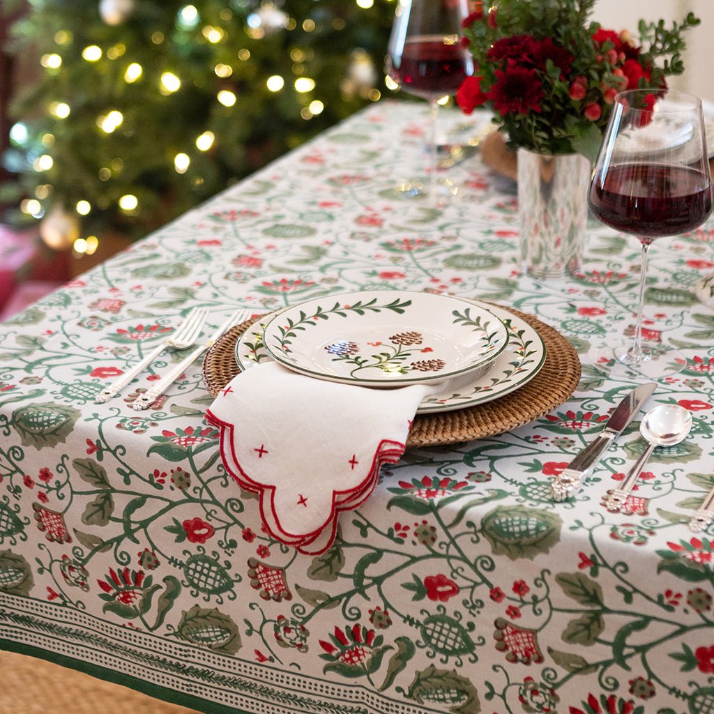 Decorative table setting with a floral tablecloth, plates, and glasses in a festive indoor setting.