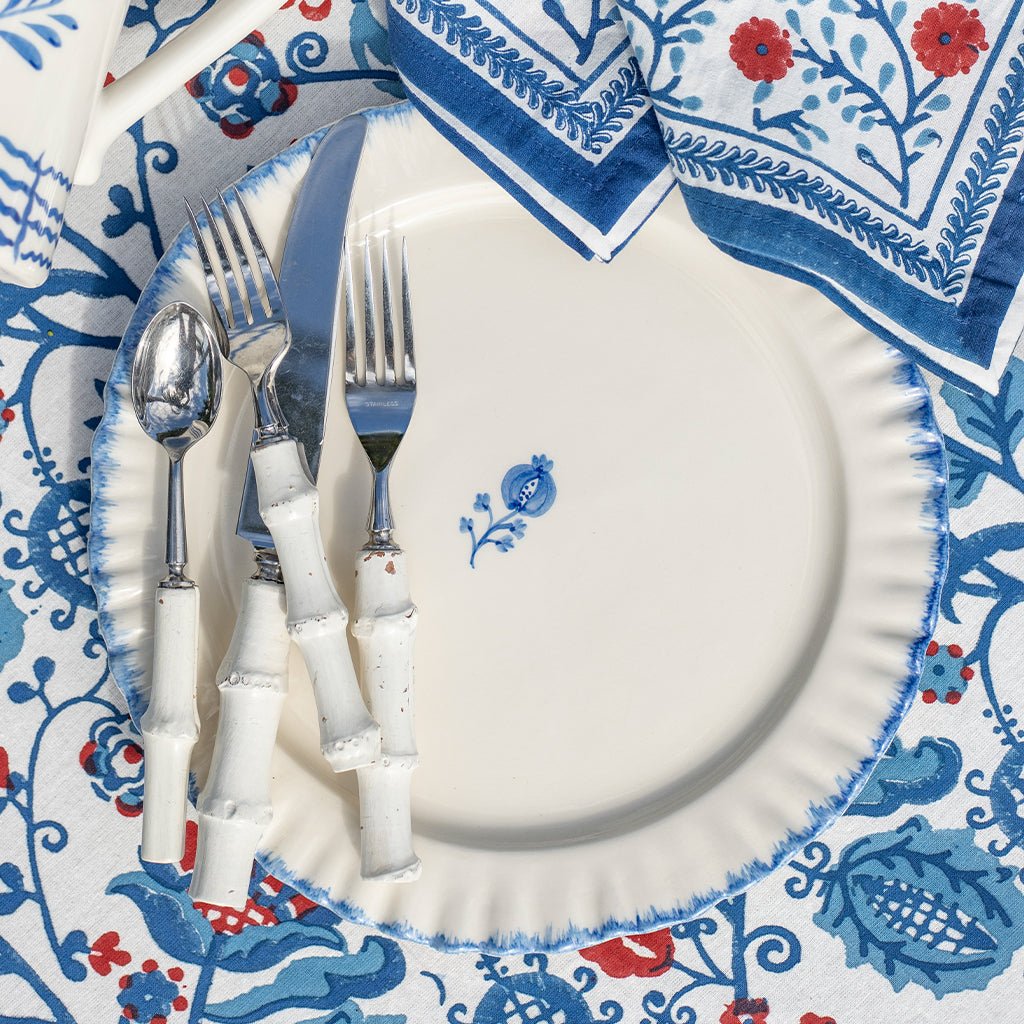 Decorative table setting with white plates, silverware, and a patterned napkin.