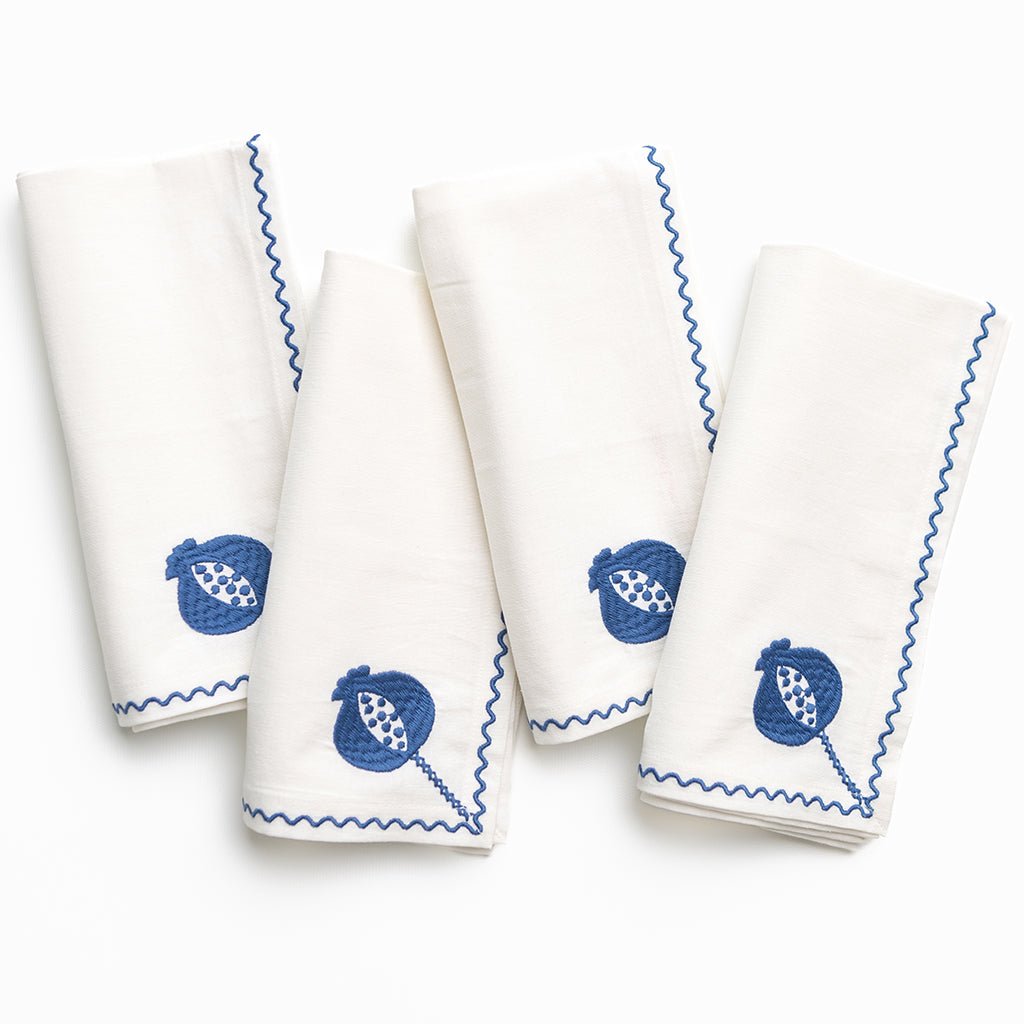 Set of four white napkins with blue patterns on a white background