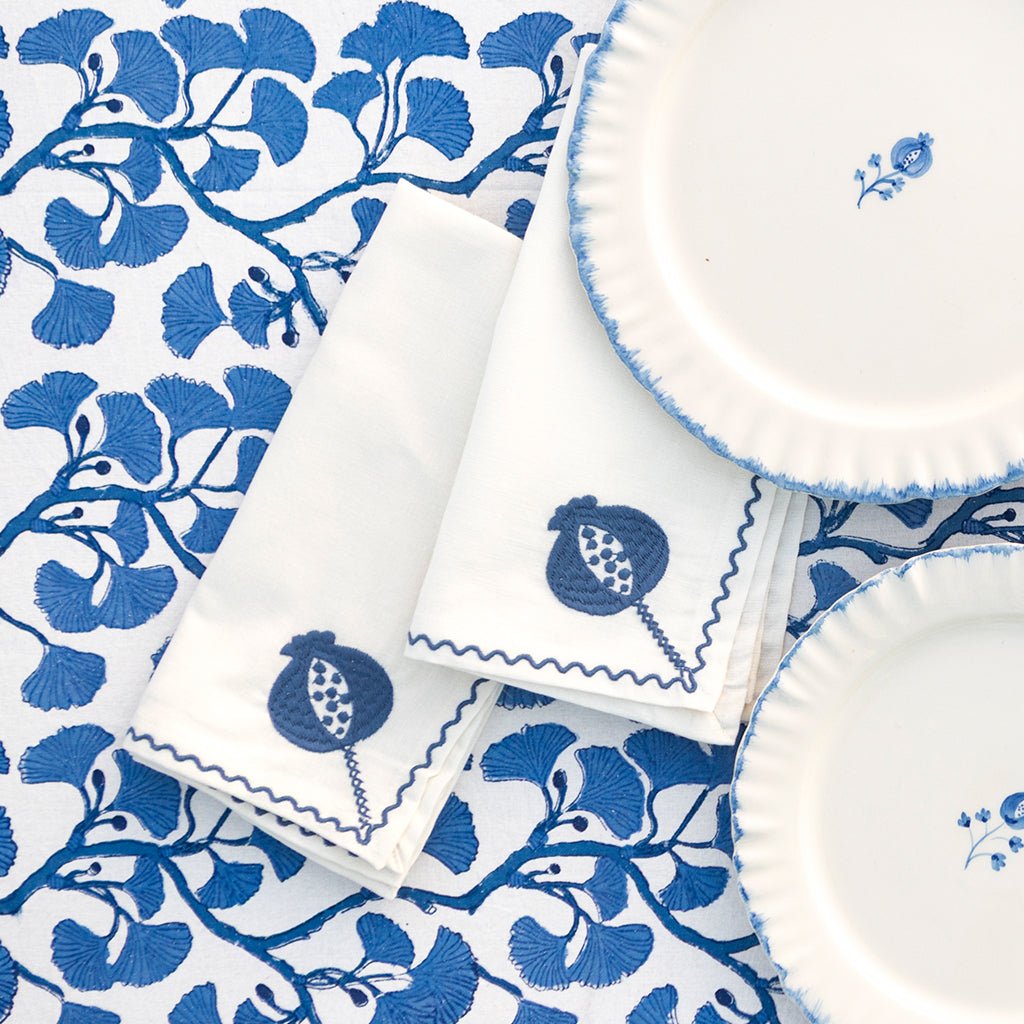 White plates and napkins with blue floral patterns on a matching fabric background