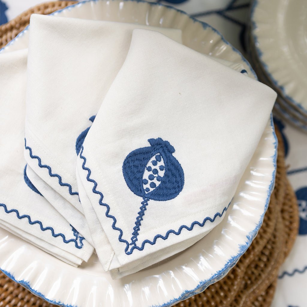 White napkins with blue embroidery on a woven placemat