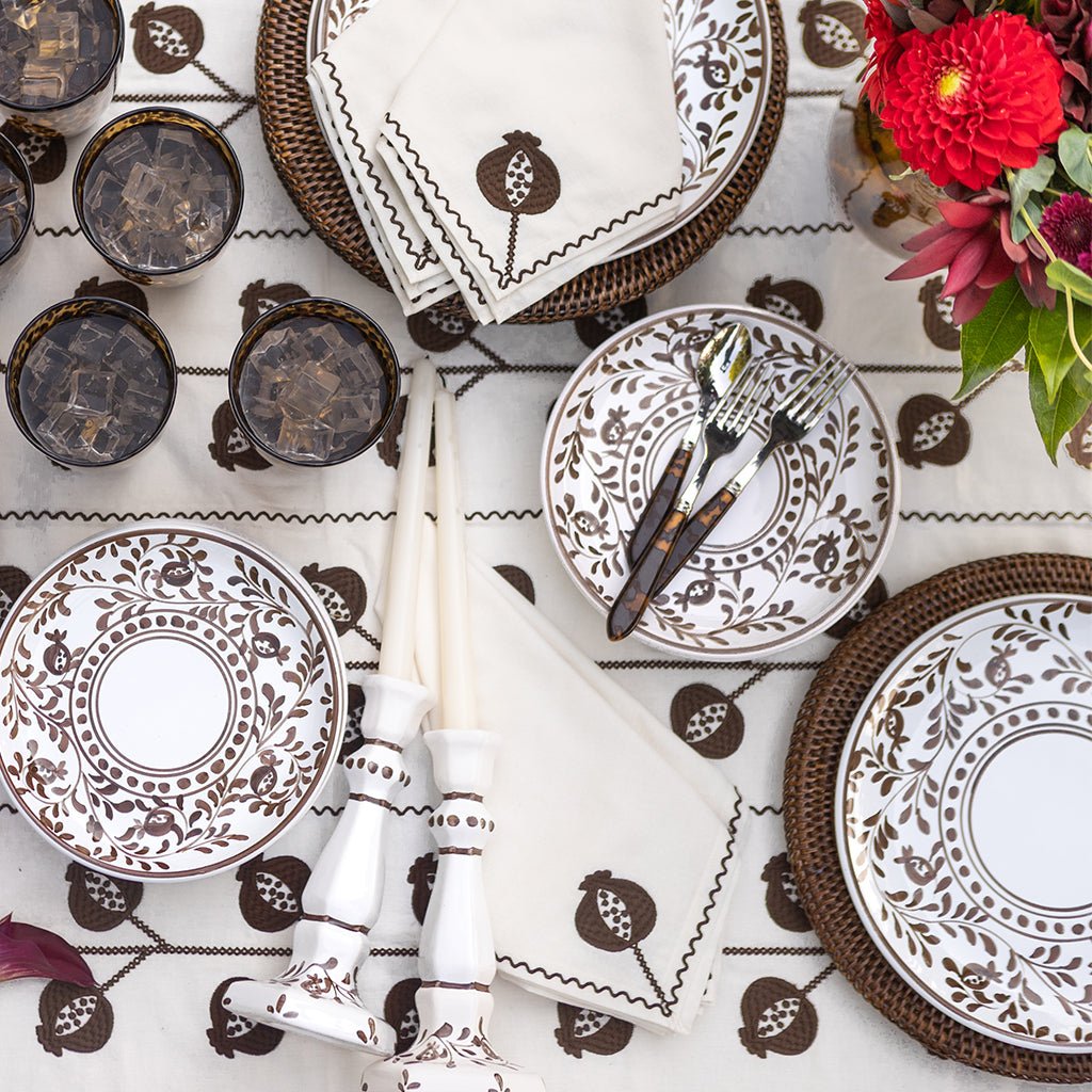 Decorative table setting with patterned plates, napkins, and cutlery on a matching tablecloth.