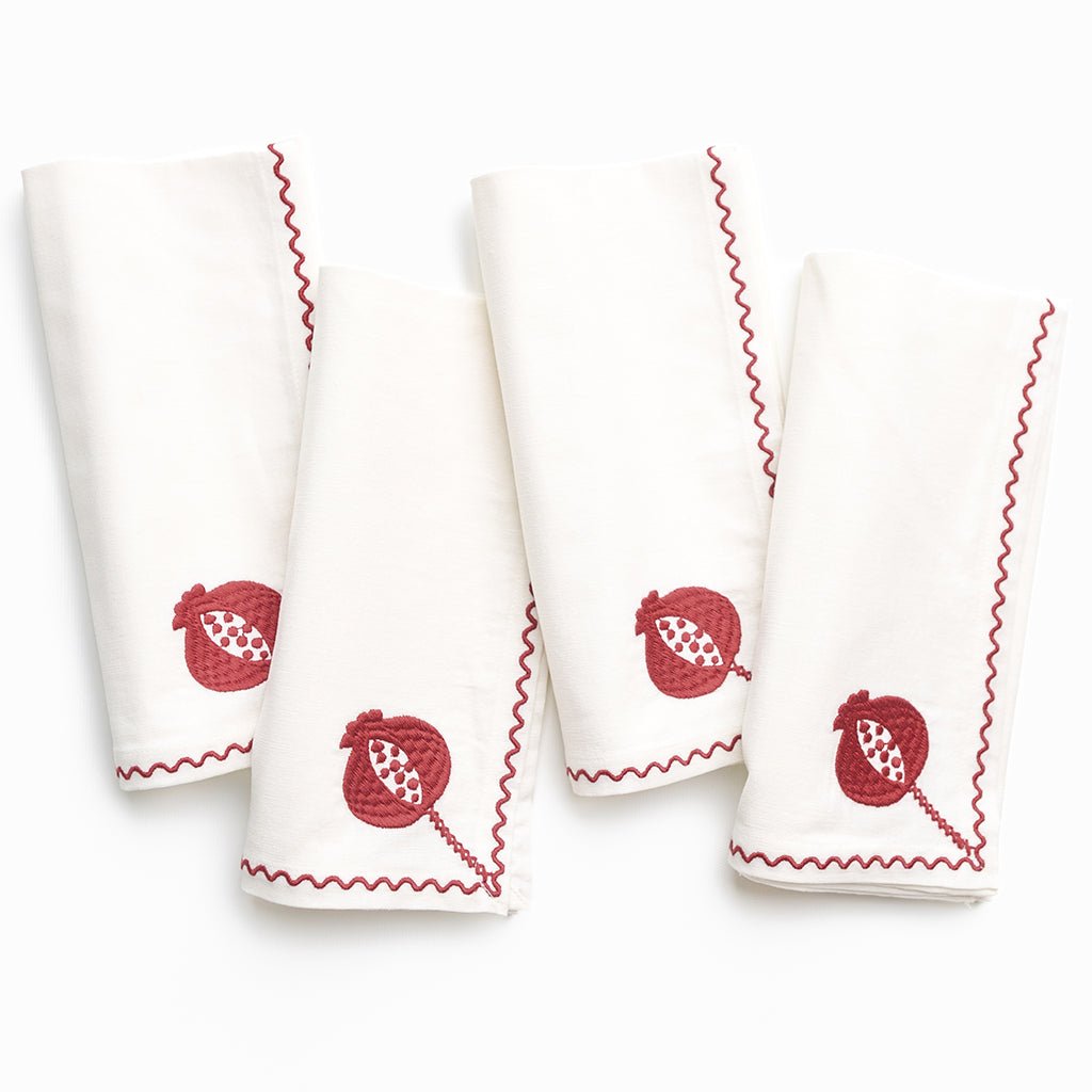 Set of four white napkins with burgundy embroidery on a white background