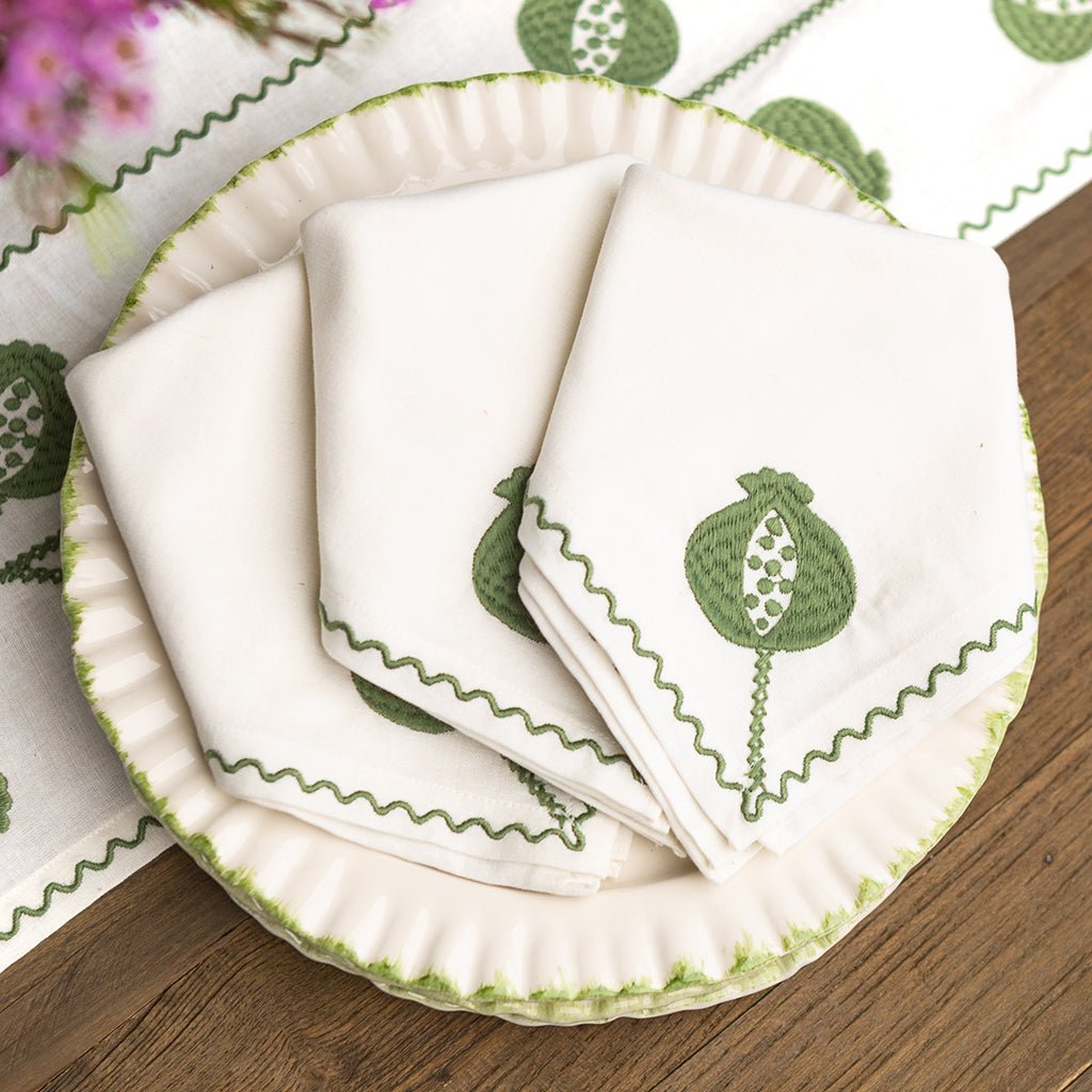 Set of white napkins with green leaf design on a matching plate.