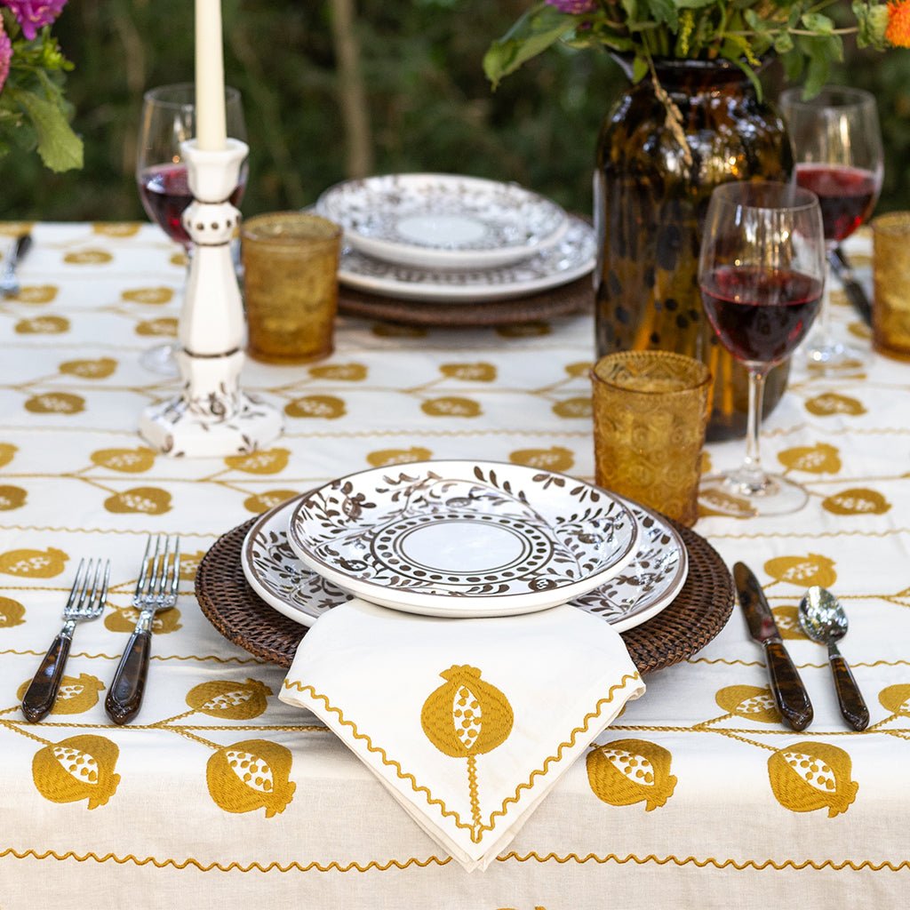 Elegant table setting with decorative plates, glasses, and cutlery on a patterned tablecloth.