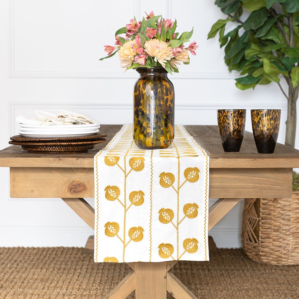 Dining table with a floral arrangement, plates, and a decorative table runner.