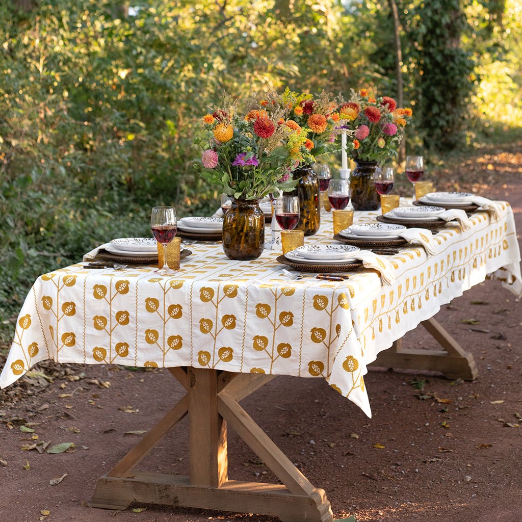 Dining table set with plates, glasses, and floral centerpieces outdoors.