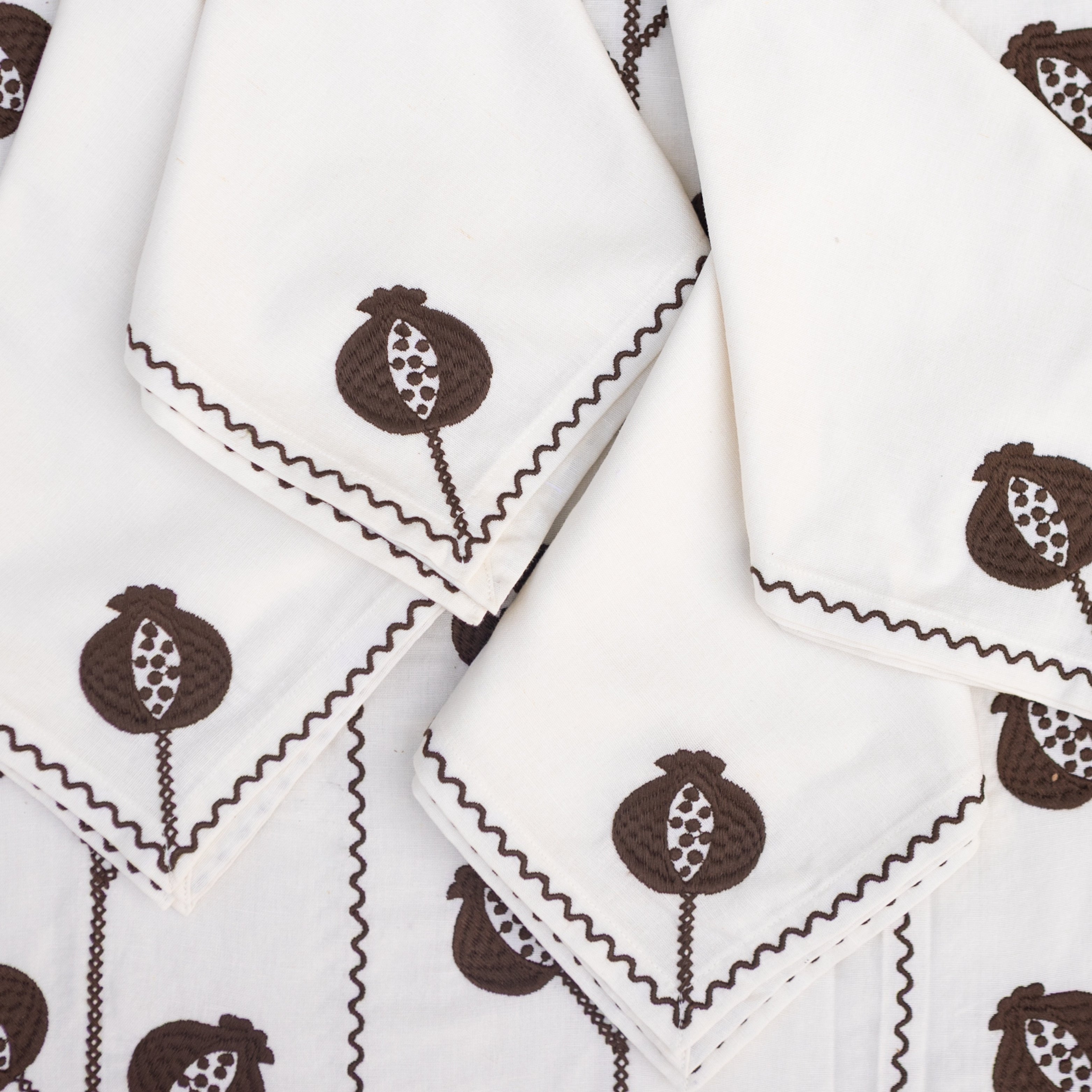 White napkins with brown pomegranate pattern on a white background