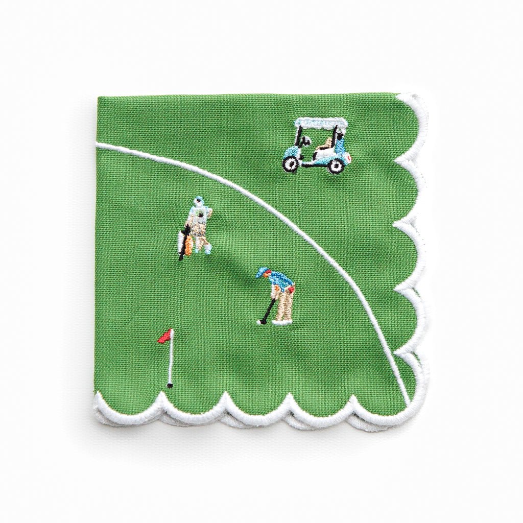 Green cocktail napkin with golf-themed embroidery on a white background