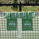 Green tea towels and cocktail napkins with pickleball design hanging on a net