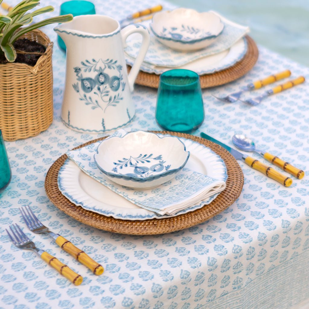 Table setting with blue and white floral-patterned dishes on a patterned tablecloth.