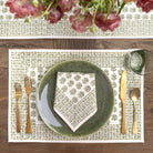 Table setting with green plates, gold cutlery, and a floral centerpiece.