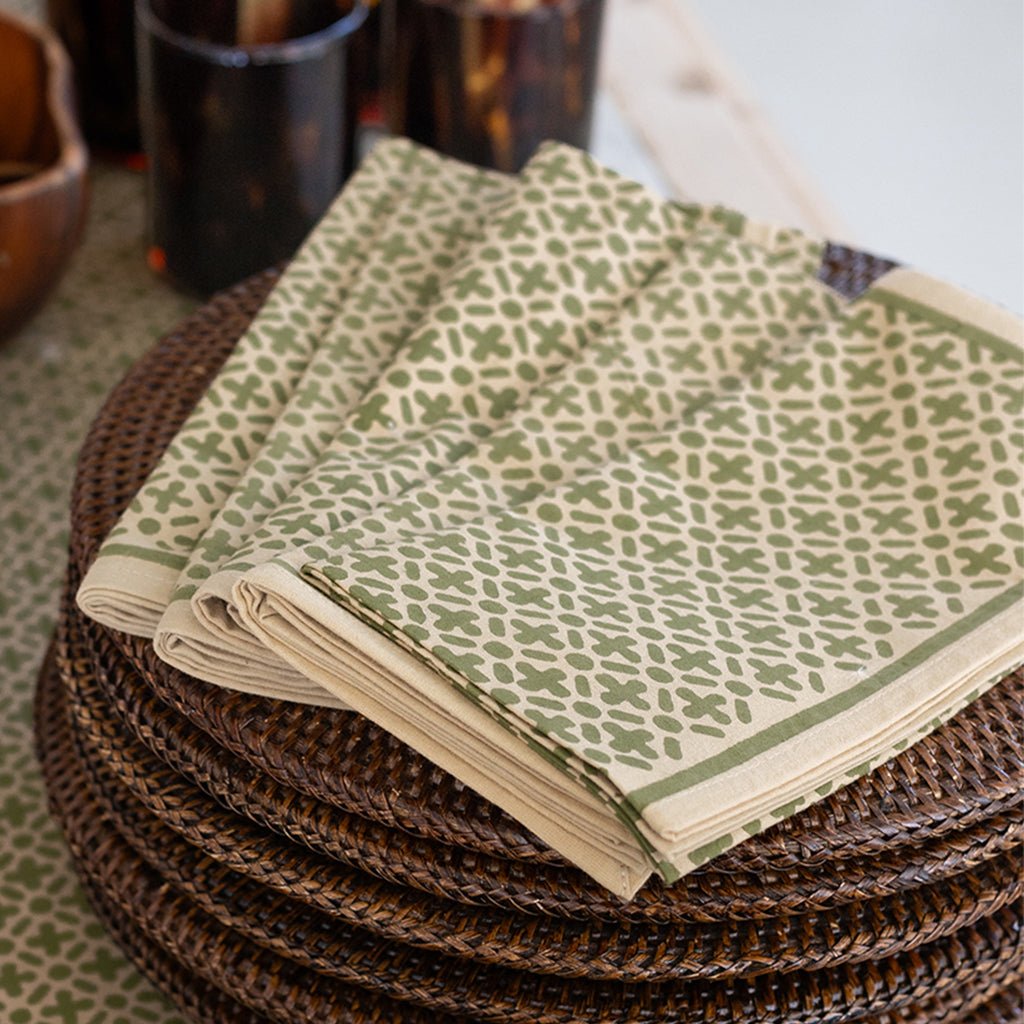 Stack of green patterned napkins on a woven surface