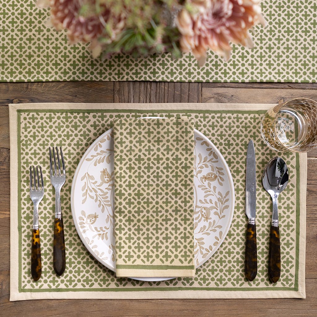 Dining table setting with patterned placemats, plates, and cutlery on a wooden surface.