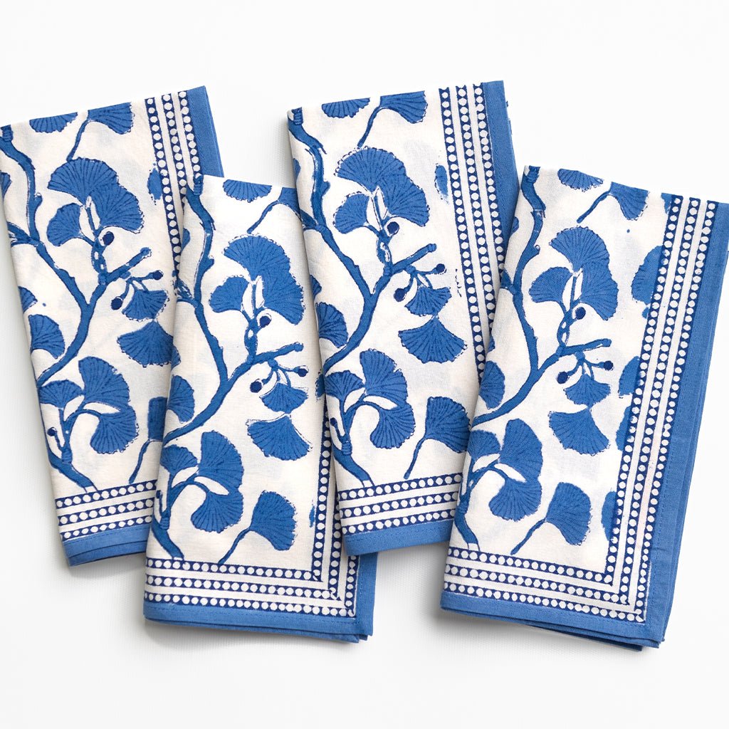 Set of four blue and white patterned napkins on a white background