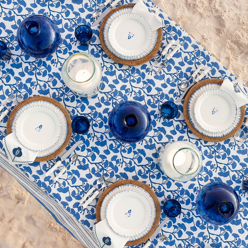 Table setting with blue and white decor on a floral tablecloth.