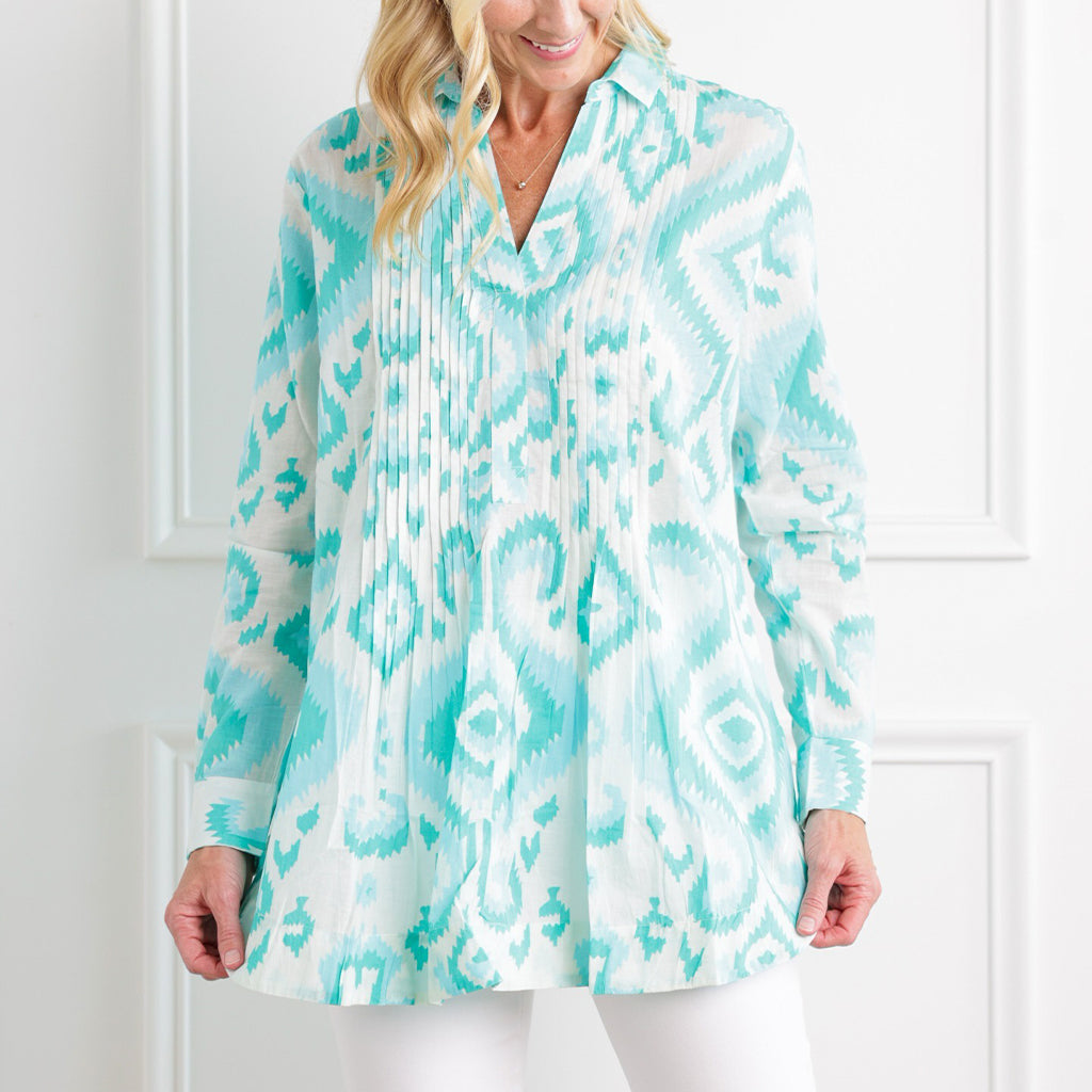 Woman wearing a turquoise and white patterned blouse against a white background