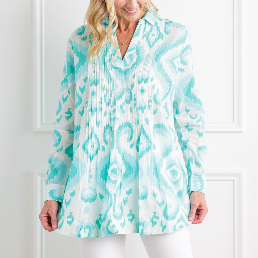 Woman wearing a turquoise and white patterned blouse against a white background