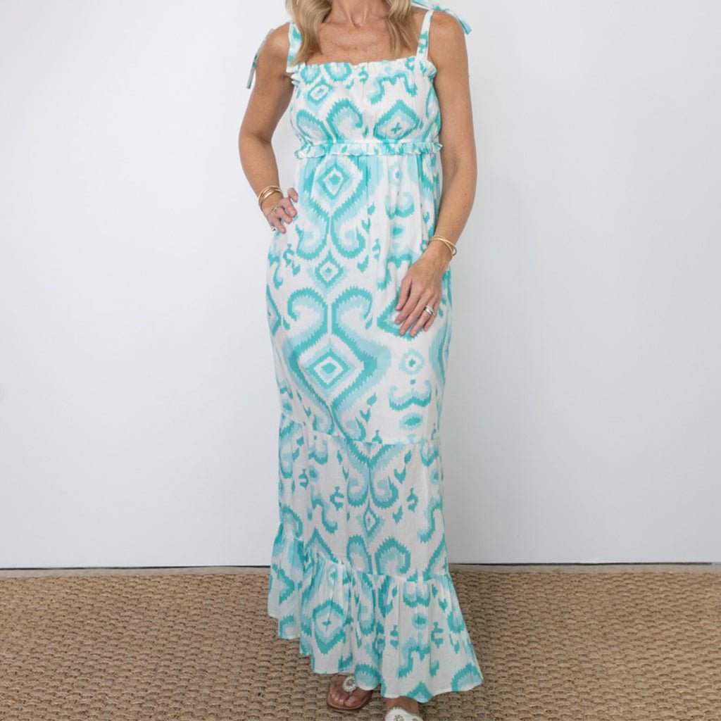 Woman wearing a turquoise and white patterned dress on a plain background
