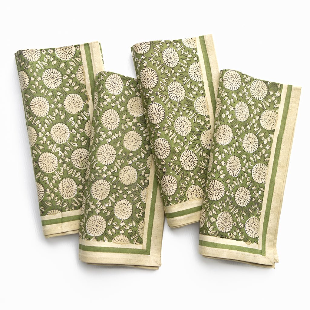 Set of four green and beige patterned napkins on a white background