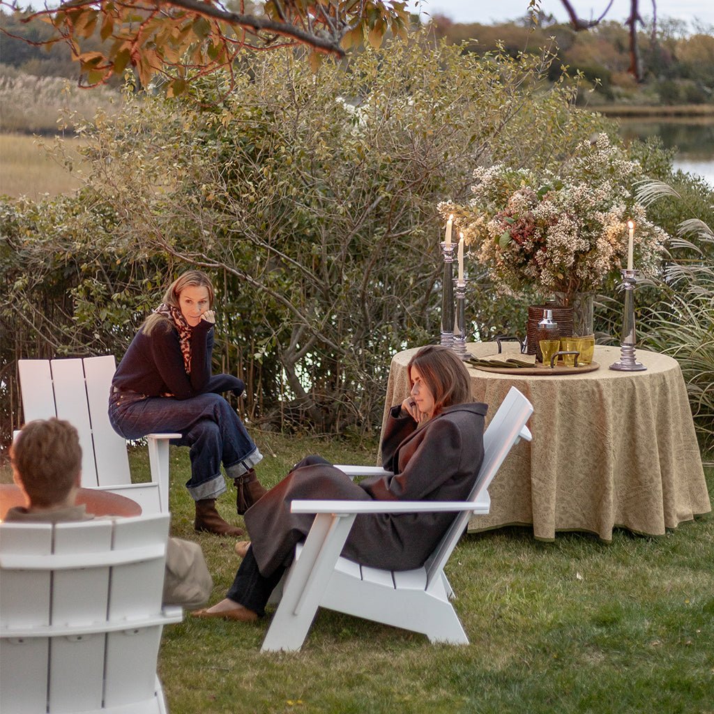 People sitting outdoors around a table with a floral arrangement and candles.