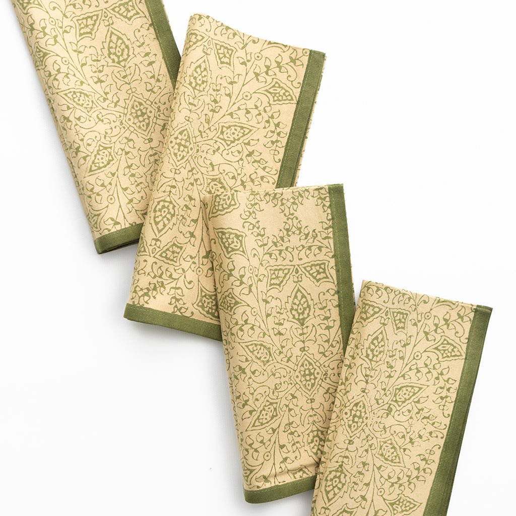 Set of four patterned napkins with green borders on a white background