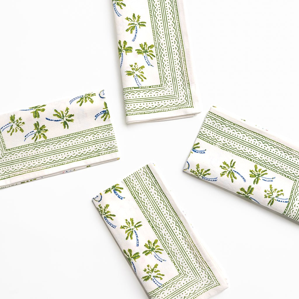 Set of four folded napkins with green floral patterns on a white background